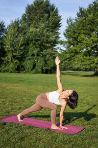 Rear view of woman doing yoga at park