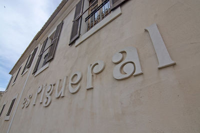 Low angle view of text on building against sky