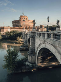 Arch bridge over river against buildings in city