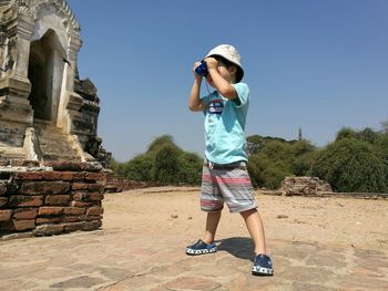 Boy looking through binoculars at historic place