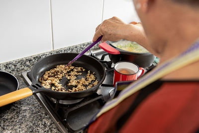 Grandma frying pine nuts and raisins in a pan.