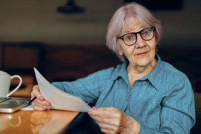 Portrait of young woman using mobile phone while sitting at home