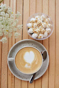 Ceramic white cup of cappuccino with heart, vegan portion of nuts dessert in a disposable cup 