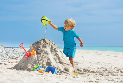 Full length of boy playing with sand at beach