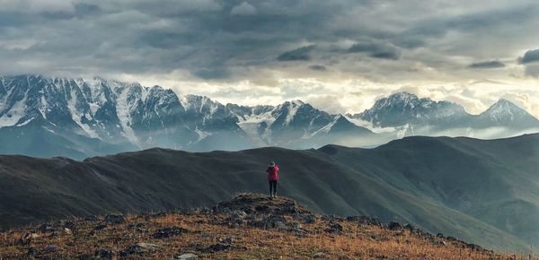 Rear view of man standing on mountain against sky