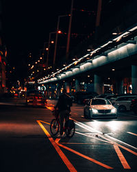 Man riding bicycle on road at night