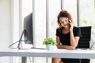 Young woman using mobile phone while sitting on table