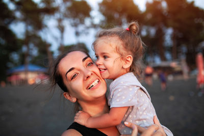 Close-up of mother carrying daughter in city