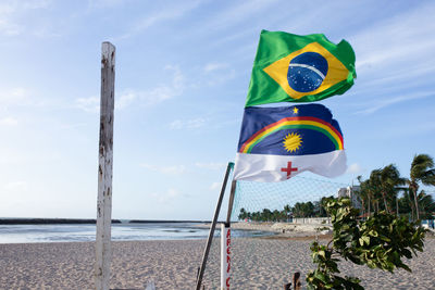 Multi colored flags at beach against sky