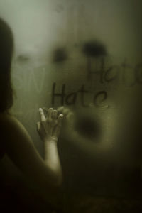 Close-up of woman writing on condensed glass