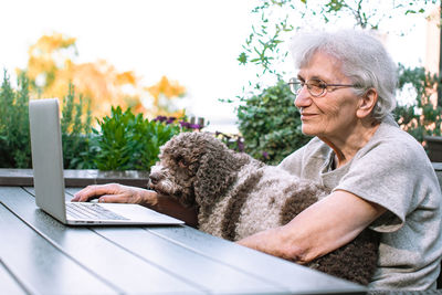 Old woman wearing face mask and her dog chatting via internet