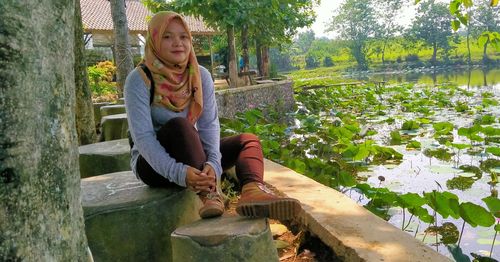 Full length of woman sitting by plants