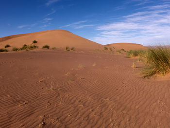 Sand dunes in desert against blue sky