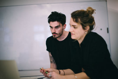 Business people discussing over laptop at desk in creative office