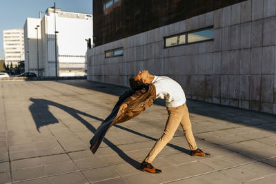 Side view of woman on footpath by street against buildings