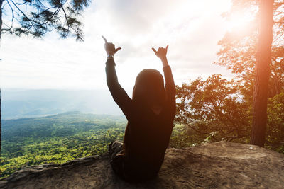 Woman with arms raised against sky