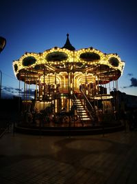 Illuminated carousel against sky at night