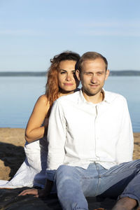 Happy international couple lies on beach. latin woman, caucasian man enjoy vacation. smiling female