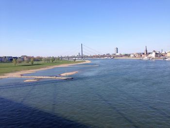 Suspension bridge over river against clear sky
