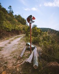 Wooden post on field by road against sky