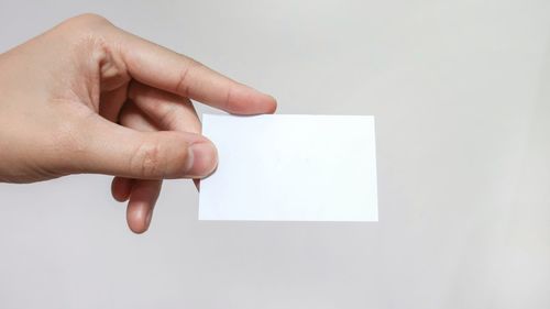 Midsection of person holding paper against white background