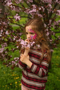 Low angle view of young woman standing against trees