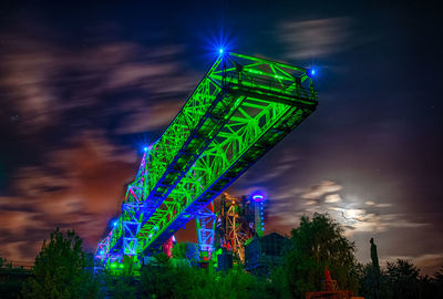 Low angle view of illuminated crane against sky at night