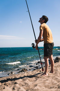 Full length of man standing at beach against sky