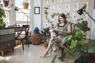 Stylish young woman reads book in her study while smiling