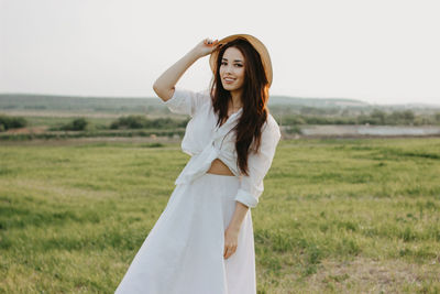 Portrait of woman standing on grass against sky