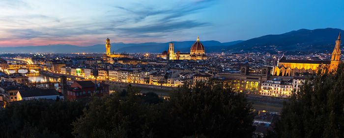 View of illuminated cityscape against sky during sunset