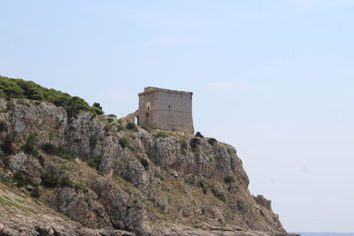 Historic building by cliff against clear sky