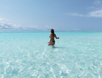 Rear view of blonde woman in shallow water of tropical sea