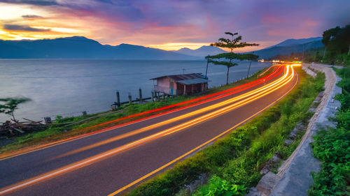 Light trails on road against sky at sunset