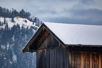 House on snow covered landscape against sky