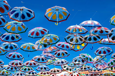 Low angle view of multi colored umbrellas against blue sky