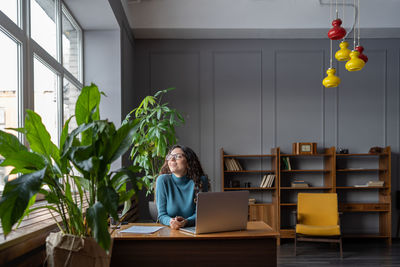 Satisfied happy female employee relaxing at workplace, happy female enjoying break during workday