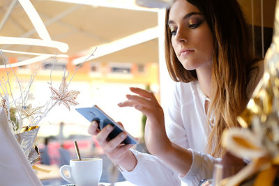 Close-up of teenager using mobile phone while sitting in restaurant