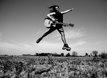 Beautiful woman jumping with her guitar