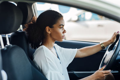 Side view of young woman sitting in car