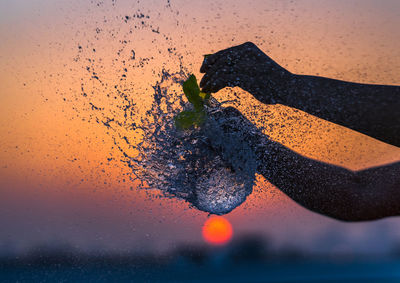 Close-up of waterdrops on glass against sunset sky