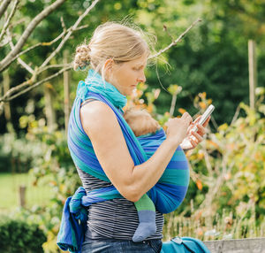 Midsection of woman holding mobile phone outdoors