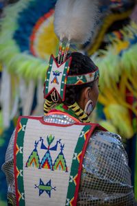 Rear view of man holding multi colored feathers