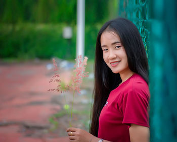Portrait of smiling woman standing by plants
