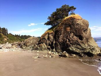 View of rocky beach against blue sky