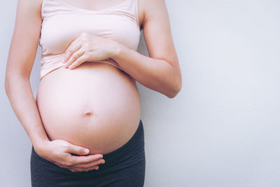 Midsection of woman touching hair against white background