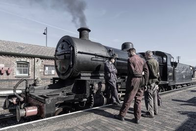 Rear view of people at train against sky