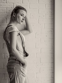 Side view of thoughtful woman standing against wall