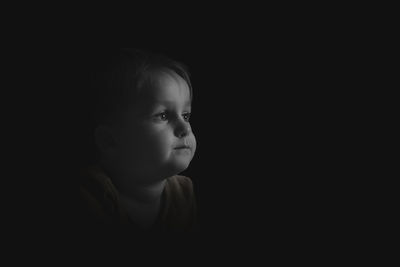 Portrait of cute boy against black background