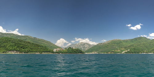 Scenic view of sea by mountain against sky